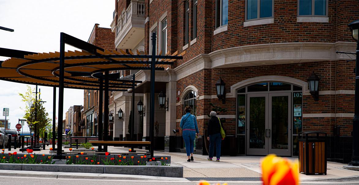 A street corner with an outdoor pergola and retail shops